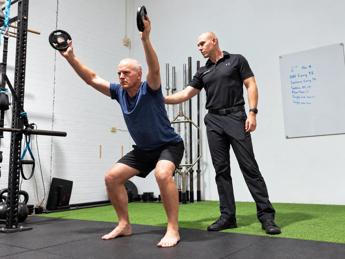 Physiotherapist supervising a patient performing an overhead squat exercise at Adaptive in Booragoon